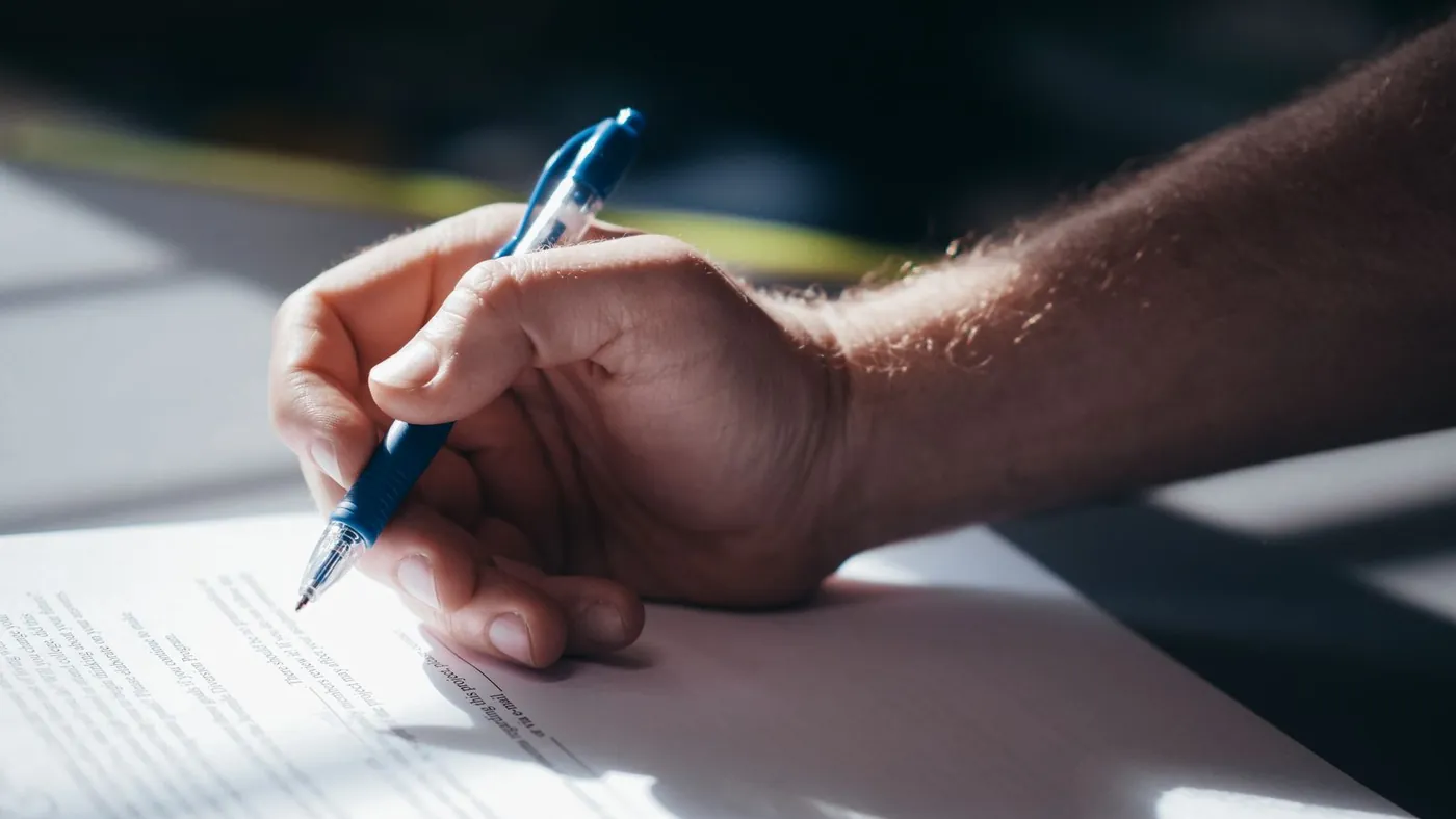 Hand signing a legal document at a desk